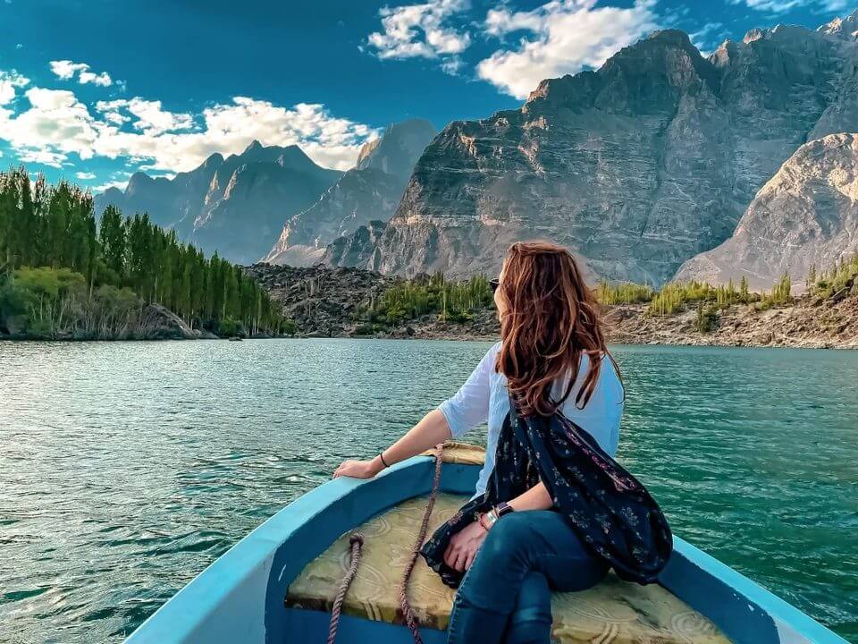 Boat on a turquoise lake below sheer rock walls, Hunza