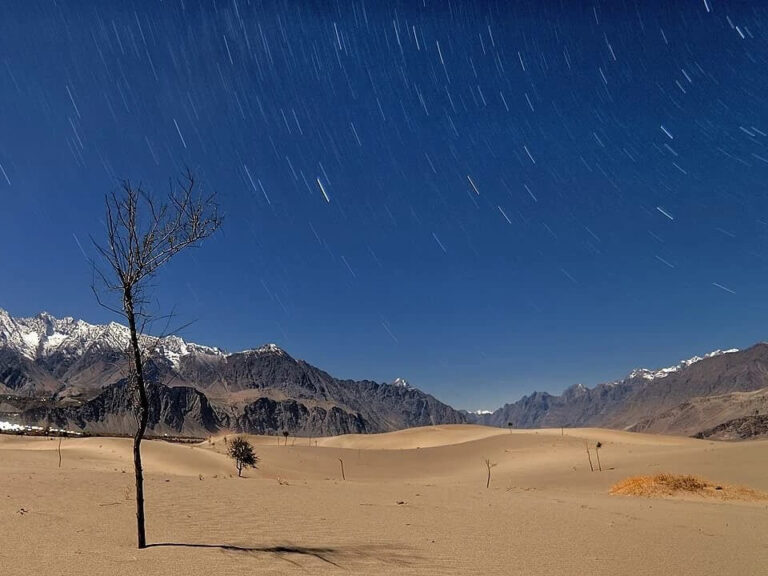 Star trails over the cold desert dunes and snow peaks, Skardu